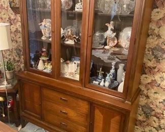 Vintage China Cabinet
Gorgeous vintage walnut MCM china cabinet / hutch (one piece) by Bassett from their Sutton Square Collection circa 1950-1960. Original brass finger pulls on all doors. Top 2 doors open and close well and do have their original magnetic hardware. The top two stationary shelves also have grooves for dishes. Glass in perfect condition. The 3 drawers on the bottom half open smoothly, are dovetailed and the top one has dividers and original felt. Behind the left bottom door is a stationary shelf and behind the right door is a large space for storage. There are a couple of scratches on the left side of the piece but overall it's really in incredible vintage condition and very stable, solid and sturdy.

DIMENSIONS:
WIDTH: 50 1/4 inches
DEPTH: 16 1/4 inches
HEIGHT: 70 inches tall.
Must be able to move and load yourself.
