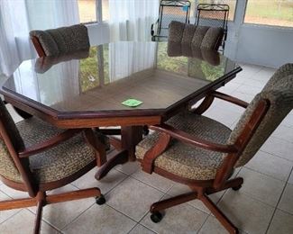 Very nice dining table with custom glass top and 4 caster, swivel chairs