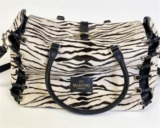 31	Valentino Garavani Leather and Zebra Purse	Authentic Valentino leather and zebra pony style calfskin satchel with buckles on the sides, silver tone hardware, removable leather shoulder strap, no marks or tears, bag appears to have been barely used. 14.5" l x 10" h x 6" w
