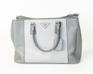 54	Prada Grey Two Tone Saffiano Lux Leather Tote	Prada Grey Two Tone Saffiano Lux Leather Large Double Zip Tote This Double Zip tote by Prada will be a loved addition to your closet. It has been crafted from two-tone grey Saffiano Lux leather and styled minimally with silver-tone hardware. It comes with two top handles, two zip compartments, and a perfectly-sized main compartment. The bag is complete with protective metal feet and the brand logo on the front. Dimensions: Height: 10.04 in. (25.5 cm) Width: 6.3 in. (16 cm) Length: 14.18 in. (36 cm) Condition Good Gently Used EXTERIOR: No real visible wear. slight streak on back left Gentle scuff on the bottom INTERIOR: Some Staining on bottom
