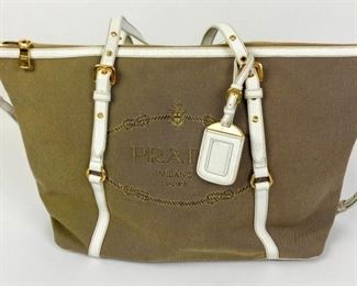 57	Prada Canvas and Leather Bag	Lot includes Prada beige canvas with white leather trim. Double leather handles on top with a 22” to 24” adjustable cross body detachable leather strap. Gold-tone hardware. Zippered closure. Prada logo at the front and ID tag. Side PRADA metal logo tag. Fabric script logo interior lining. Two interior compartments one zippered. 12"H, 18"W, 5"D, good condition, some minor marks from use.
