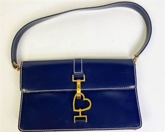 202	Moschino Blue Purse	Blue and red leather with gold tone heart latch. Red fabric lining with pocket. Some marks and dents in the leather and by latch. 9.5" l x 6" w x 1.5" d
