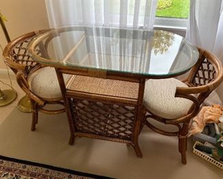 Vintage glass-top rattan table with two chairs.