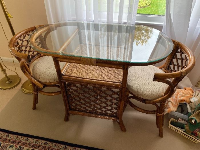 Vintage glass-top rattan table with two chairs.