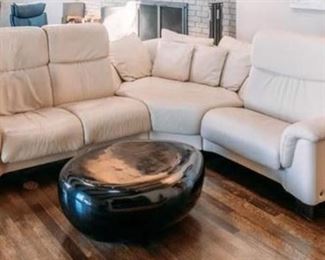 Ekornes Stressless sectional in ivory white leather. Three piece. 2-seat section 61" wide. One-seat section 36" wide. Middle section 54" wide. $2,800. River Stone Cocktail table with black gel coat. 40" long x 25" wide x 14" tall. $500