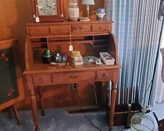 Stuart-Temple, Tell City maple roll top desk. To the left is a tilt top card table.