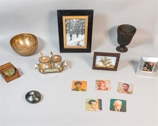 305	Grouping of Decorative Accessories	Grouping of 9 decorative tabletop items. Glass and silverplate condiment jars in a silverplate holder, metal singing bowl, small Indian bowl, set of 6 wood and glass hand painted coasters in wooden holder, set of 5 cardboard coasters, square silver tone frame with floral print, wooden frame with police photo print, wooden frame with hunting scene photo print, cast iron vase. Singing bowl 3 3/4"H x 8 1/4"-diameter, largest frame 12" x 10" (opening 8" x 6"), cast iron piece 6 3/4"H. 1 handle cracked on condiment set (piece present).
