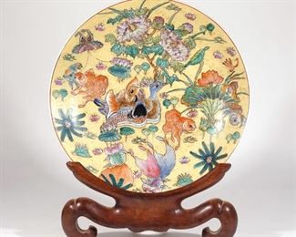 Lot 84 | FAMILLE VERTE MONUMENTAL CHARGER | 19th/20th century, Japanese, ornately and finely decorated with colorful ducks, goldfish, butterflies, and peonies; with a carved conforming stand; dia. 18 in.; overall: 22-1/2 x 18 x 7 in. (on stand)