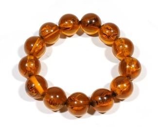 Lot 91 | AMBER SPECIMEN BRACELET | 13 amber beads with insect specimens strung on elastic; approx. bead dia. 17.9mm., 47.5g; dia. 2-1/2 in. (approx. inner); overall: dia. 3-3/4 in. (approx. outer)