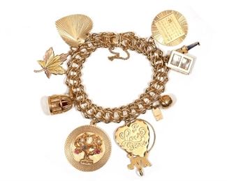 Lot 120 | GOLD CHARM BRACELET | With heart, leaf, birdcage, apple, deck of cards, and other charms; l. 7 in., 56.6g