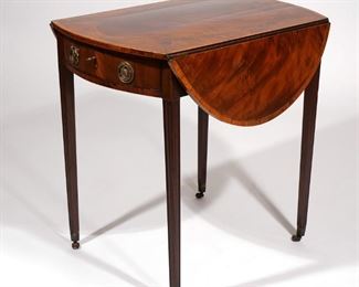 Lot 151 | SHERATON INLAID FLAME MAHOGANY OVAL PEMBROKE TABLE | C. 1810, top with oval line inlay and banded satinwood border and bowed ends, over single drawer addorsed with false drawer, resting on square tapering fluted legs ending in brass boots with casters
h. 27-1/2 w. 36-1/4 d. 28 in.
