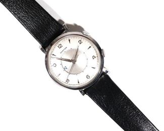 Lot 286 | CARTIER MEMOVOX [LE-COULTRE] WRISTWATCH | c. 1950s stainless steel case (diameter 35mm), white dial with silver Arabic and dagger numerals, lozenge hands, silver central rotating subdial with blue painted arrowhead for alarm setting, face signed "CARTIER" in block letters, manual wind movement with hour, minute, second, and second crown for alarm setting; s/n 593455