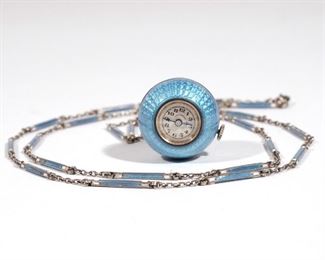 Lot 291 | ENAMEL & SILVER BALL PENDANT WATCH | Blue guilloche enameled ball watch pendant with blue and white enamel bar and silver chain, the face with Arabic numerals and marked "C. Bucherer"