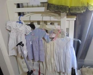 Several cute vintage girl's dresses, white baby crib.