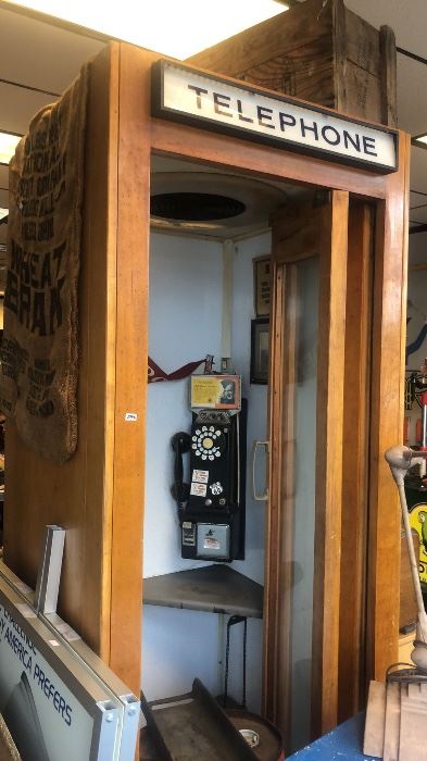1940s Wooden Phone Booth with vintage advertisement above phone.