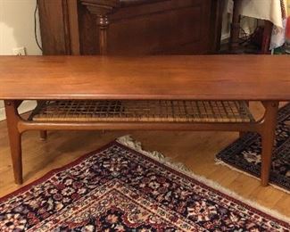 Danish teak & cane coffee table by Trioh Mobler - with cane shelf below top  (59”L, 17”H, 20.5”D) 