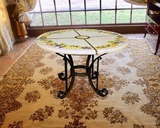 Very Large Porcelinized Terra Cotta Table with Hand Wrought Iron Base. Beautifully hand painted of various fruits and brass bound top. Artist Signed. 54 inch diameter