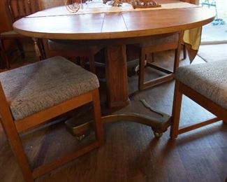 Solid oak dining room table, 4 upholstered chairs - brass base, rolling casters, expands (round to oval) with leaves