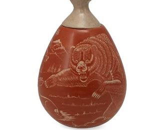 6054
A Thomas Polacca Nampeyo Hopi Sgraffito Lidded Jar
(1935-2003, Hopi)
Signed: Thomas Polacca / 12-75-001 / Nampeyo
The bulbous jar with red slip glaze sgraffito carved with two bears and deer in a landscape with a buff polished lid in the form of a bear paw with inset turquoise stone
7.5" H x 5" Dia.
Estimate: $300 - $500