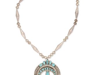 6098
A Nelson Tapia Navajo Squash Blossom Necklace
20th/21st Century, Diné
Stamped: NT [Nelson Tapia]
Designed with fully stamped silver beaded chain finished with an elaborate turquoise-set naja
26" L x 3.5" H
113.9 grams
Estimate: $400 - $600