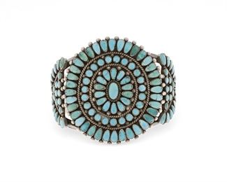 6107
An Old Pawn Zuni Cluster Bracelet
Mid-20th Century
Etched: Doris Yazzie / 17490
Three bands of turquoise centering an oval center stone with side plaques all set to a three wire backing
6.625" total inner C x 2.5" H, wrist opening: 1.25"
76.8 grams
Estimate: $400 - $600
