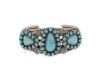 6111
A Gary Reeves Navajo Cluster Turquoise And Silver Cuff
(1962-2014, Diné)
Stamped terminals: G. Reeves / Sterling
A five wire cuff featuring three plaques of cluster set Lone Mountain turquoise with applied wire and silver stampwork decoration
6.5" total inner C x 1.375" H, wrist opening: 1"
92.7 grams
Estimate: $400 - $600
