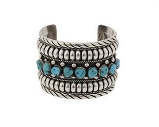 6114
A Delbert Gordon Navajo Silver And Turquoise Cuff Bracelet
(b. 1955, Diné)
Stamped: D. Gordon / Sterling
Featuring nine nugget turquoise stones set into a wide silver cuff
7.5" total inner C x 2.25" H, wrist opening: 1.5"
143.6 grams
Estimate: $300 - $500