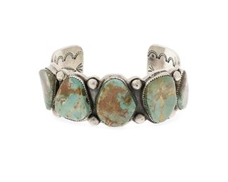 6115
A Large Lee Bennett Navajo Silver And Turquoise Cuff Bracelet
Second-Half 20th Century, Diné
Stamped: L. Bennett / Sterling
An ingot silver cuff featuring five tumbled Royston turquoise stones with elaborately stamped terminals and interior
7.75" total inner C x 1.25" H, wrist opening: 1.5"
142.4 grams
Estimate: $400 - $600