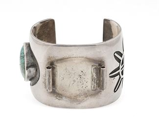 6123
A Virgil Thomas Hopi Silver Overlay Watch Cuff
Fourth-Quarter 20th Century
Stamped: star pictograph [for Virgil Thomas] / conjoined HC [for Hopicrafts Guild]
A large watch cuff featuring silver overlay designs of a Hopi Tewa face and waves with a bezel set turquoise stone
7" total inner C x 2" H, wrist opening: 1.375"
124.1 grams gross
Estimate: $200 - $400