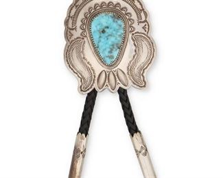 6127
A Terry Martinez Navajo Silver And Turquoise Bolo Tie
Late 20th/Early 21st Century, Diné
Stamped: TM / Sterling
A large silver bolo with an inverted teardrop Morena turquoise stone and cylindrical tips all suspended on a black braided leather cord
Bolo: 3.5" H x 3" W
121.7 grams
Estimate: $400 - $600