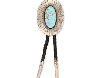 6128
A Terry Martinez Navajo Silver And Turquoise Bolo Tie
Late 20th/Early 21st Century, Diné
Stamped: TM [Terry Martinez] / Sterling
An oval silver bolo with hand-chiseled feather motif set with a large oval cabochon number 8 turquoise, with a figure eight wire fitting and stamped cross motif on reverse, finished with tapered and stamped enhanced tips, all mounted to a braided black strap
Bolo: 3.5" H x 2.5" W
145 grams
Estimate: $400 - $600