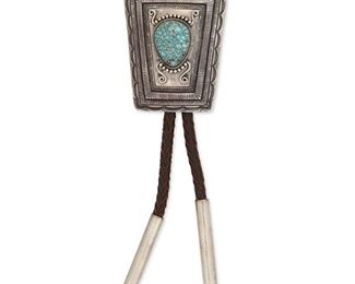 6129
A Howard Nelson Navajo Silver Bolo Tie
Late 20th/Early 21st Century, Diné
Stamped: Howard [Howard Nelson] / Sterling
A trapezoidal bolo with stamped and applied motifs set with a teardrop turquoise cabochon, finished with cylindrical tips and mounted by a figure eight wire fitting on a dark brown braided cord
2.75" H x 2.25" W
113 grams
Estimate: $400 - $600