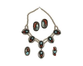 6148
A Group Of Of Southwest Silver Jewelry
Second-Half 20th Century
Three works:

A double strand beaded necklace with stone set coral and turquoise oval plaques with applied feather elements
Etched: Bobby Thompson
17" L x 3.5" H

A pair of oval clip earrings with stone set coral and turquoise
Appear unmarked
1.75" L x 1.25" W

Two coral and turquoise rings with applied stampwork and wire work designs
Each appear unmarked
Oval ring: ring size: 12; 1.75" H x 1" W; Narrow ring: Ring size: 11; 1.75" H x 0.375" W

5 pieces
134.1 grams
Estimate: $400 - $600