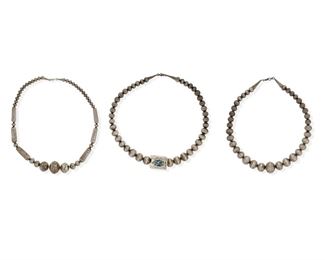 6149
A Group Of Three Southwest Silver Beaded Necklaces
Second-Half 20th Century
Each appears unmarked
Comprised of a single strand of graduated stampwork beads with a large rectangular center bead set with an oval turquoise stone with heavy matrix (28" L x 1.125" H), a single strand of graduated round and cylindrical stampwork beads (28" L x 1.125" H), and a single strand of stamped beads (25" L x 1.25" H), 3 pieces
416.1 grams gross
Estimate: $300 - $500