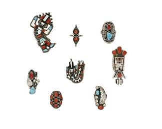 6167
A Group Of Southwest Rings
Second-Half 20th Century
Eight works:

A large rainbow kachina figure ring with multi stone bezel set inlay
Stamped: IHMSS [for Indian Hand Made Sterling Silver]
Ring size: 7.5; 2.375" L x 1.5" W

A rainbow kachina figure ring of multi stone set inlay
Etched: H. E. Cellicion / Zuni [for Herbert and Esther Cellicion]
Ring size: 6; 1.5" L x 1.25" W

A sculptural standing kachina figure ring with stone set coral
Etched signature: D. S_____ [probably Doris Smallcanyon, Navajo/Diné]
Ring size: 7.25; 2.5" L x 1"

A large coral and turquoise stone set ring with feather and rope wire accents
Stamped: B [within arrowhead, for Birdie Desiderin, Navajo/Diné]
Ring size: 12; 1.375" L

A narrow ring of bezel set turquoise and coral with feather and wirework accents
Stamped: Phil Chapo [Navajo/Diné]
Ring size: 7; 1.5" L

A sculptural ring with stone set turquoise and coral and feather stampwork
Appears unmarked
Ring size: 7

An oval coral cluster set ring
Stamped: B [f