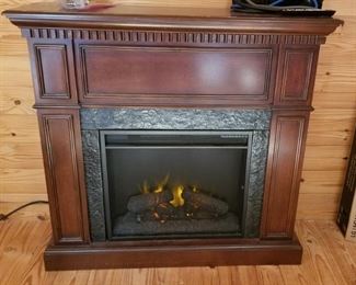 Free standing fireplace mantel with electric logs.