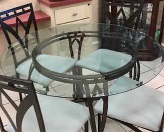 Glass topped dining table with four chairs.