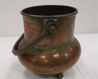 COPPER AND BRASS FOOTED BUCKET WITH ROPE MOTIF HANDLE. DOVE TAIL CONSTRUCTION ON THE SIDES . 9.5" TALL EXCLUDING THE HANDLE. UNSIGNED. SURFACE ON RIM OF BASE. SOME DENTS