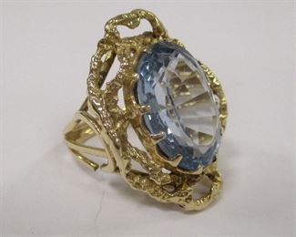 14K YELLOW GOLD RING WITH BLUE TOPAZ COLOR STONE. SIZE 6 1/4. WEIGHT 10.8 GRAMS. ONE AREA OF SHANK SEPARATED