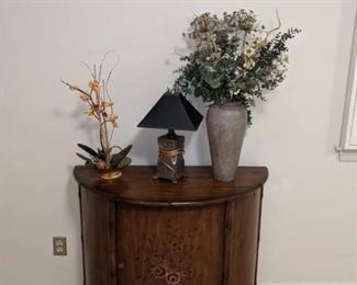 SWEET DEMILUNE STYLE CABINET WITH SUBTLE FLORAL DESIGN ON DOORS.