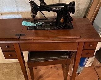 Singer sewing machine with cabinet and bench.