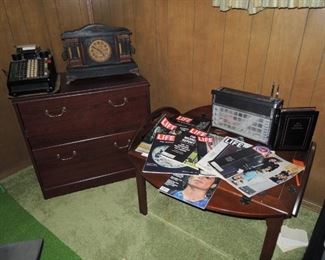 wood file cabinet, butler/valet table, retro radio, magazines.  Old clock and business machine