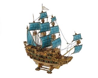 1060
A Viennese Enameled And Gilt-Silver Nef Centerpiece
Late 19th/Early 20th Century
Appears unmarked
Possibly Austrian, the gilt-silver ship centerpiece with enameled hull and sails, the hull set with semi-precious stones
13" H x 10.25" W x 4" D
Estimate: $3,000 - $5,000