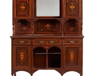 1168
An English Edwardian Marquetry Cabinet
First-Quarter 20th Century
The oak cabinet with two upper cupboards surmounted by gallery rails and centering a beveled glass mirror with shelf and baluster supports, over a lower cabinet with three drawers with brass pulls atop two cabinets flanking a central pigeonhole, raised on six carved legs joined by an undershelf, with all-over kingwood, fruitwood, and satinwood inlay depicting various Classical vessels
81.5" H x 48" W x 15" D
Estimate: $2,000 - $3,000