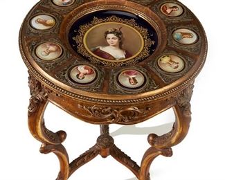 1244
A Giltwood Side Table With Royal Vienna Porcelain Plaques
Late 19th/Early 20th Century
Centering a portrait of Louise Bénédicte de Bourbon, Duchesse de Maine with a border of ten portrait plaques of various queens and Duchesses of Europe set into a carved giltwood table with cabriole legs joined by a carved stretcher
30.5" H x 20.5" Dia.
Estimate: $3,000 - $5,000