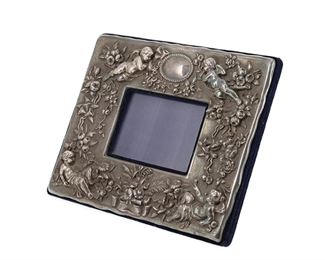 1261
A Sterling Silver Repoussé Picture Frame
First-Quarter 20th Century
Marked for sterling with indistinct maker's mark
The rectangular table top picture frame with Romantic-style repousse putti and floral sprays centering an oval cartouche mounted to a blue velvet backing
Frame: 8.625" H x 10.75" W x 4.5" D; Opening: 3.25" H x 4.625" W
28.105 gross oz. troy approximately
Estimate: $600 - $900