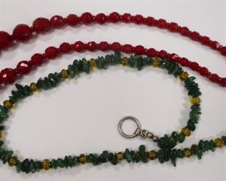 AN OPAQUE RICH RUBY RED FACETED GLASS NECKLACE.  16".  If you visit our office, make sure to see this one in person.  The red color is amazing
A 16" NECKLACE WITH NATURAL GREEN AVENTURINE TYPE STONES AND AMBER GLASS SPACERS.  UNMARKED SILVER CLASP