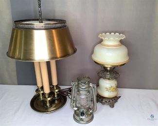 Lamps
Two (2) electric and one (1) battery operated. Brass colored lamp with three candle stems and brass colored shade. Plastic stems covered cracked at top. Victorian design glass & metal lamp with yellow flowers. Small cracking on top glass portion. Both electrical lamps turn on when plugged in. One (1) silver colored tin like battery operated lantern. Unknown if works