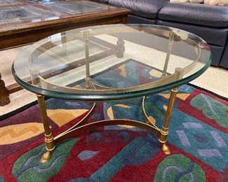 Coffee/cocktail table with brass base and glass top.