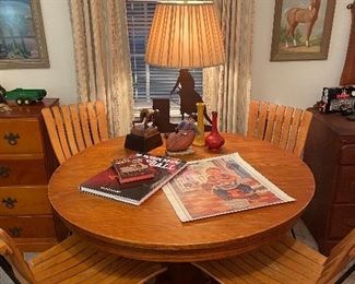 Pedestal round oak table w/ a set of 4 mid century pine and wrought iron chairs, bronze track runner statue and cowboy lamp 